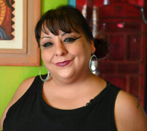 Woman dressed in black standing in front of a green wall
